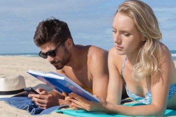 people on sunbed reading book on the beach