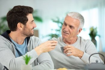 adult son helping senior father at home