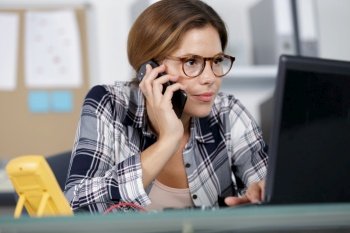 concentrated woman using laptop and phone