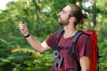 man holding his phone out in the woods