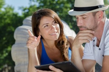 romantic couple looking at tablet computer outdoors