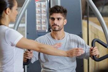 gym trainer showing right position to use gym machine