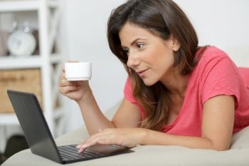 woman with laptop and coffee in bed