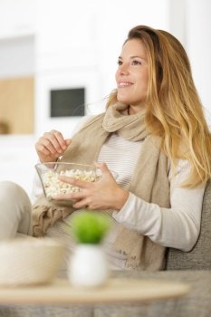 young woman watching tv and eating popcorn