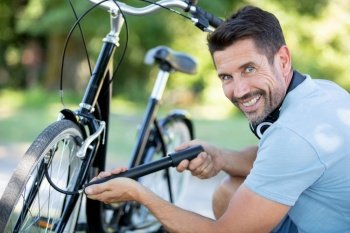 portrait of handsome man pumping bicycle tires at park