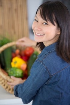 asian woman with a basket of summer vegetables