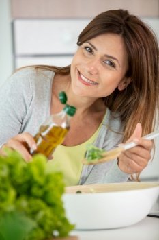 woman eating vegetable salad at table in kitchen healthy diet