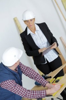 female manager inspecting male carpenter