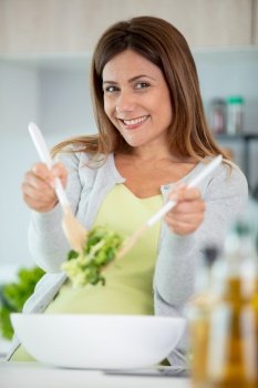 happy woman putting ingredients into the bowl