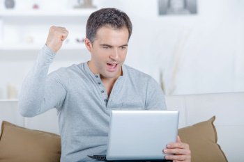 Man using a laptop and raising his fist