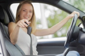 young woman sitting in new car showing car keys