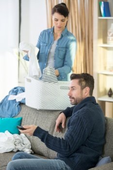 young woman doing laundry with boyfriend watching tv