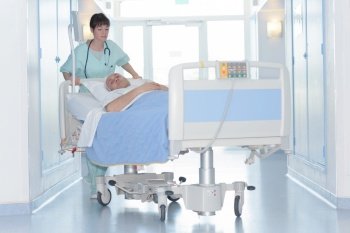 nurse pushing patient bed corridor