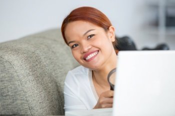lady on sofa with laptop holding a magnifying glass