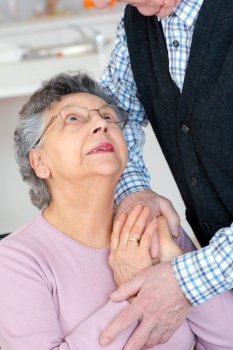 elderly woman looking up and husband while holding his hand