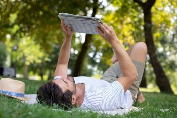 man reading a newspaper while sitting on a green meadow