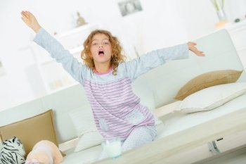 Young girl on sofa stretching and yawning