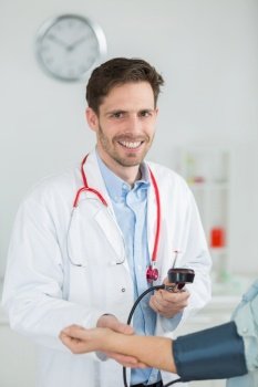 portrait of happy doctor checking patients blood pressure in clinic