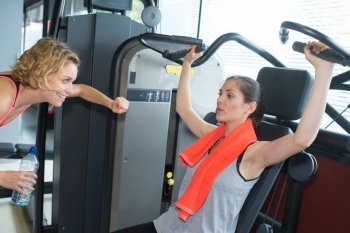 female trainer assisting woman exercise in the gym