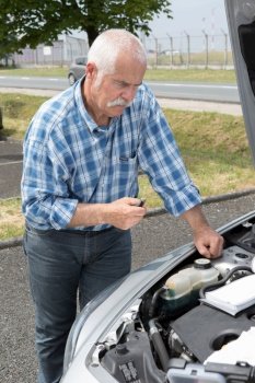 older man checking levels and servicing his car