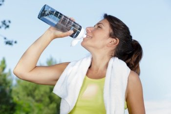 fitness woman drinking water after jogging in the morning
