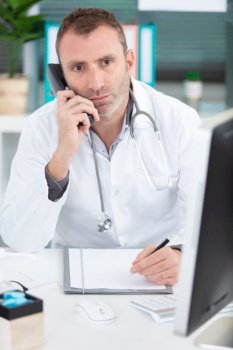 attractive male doctor talking on the phone in his office