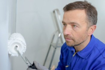 Man painting a wall white