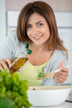 woman at home pouring dressing on salad