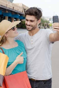couple taking selfie in street while out shopping