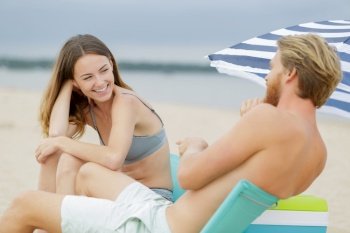young couple sat laughing on the beach