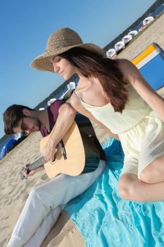 young man with his guitar and girlfriend on the beach