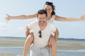 lovestory of beautiful couple piggybacking on the beach