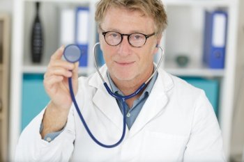 funny male doctor wearing glasses and sthetoscope smiling to camera