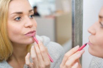 woman applying lip colour with pencil