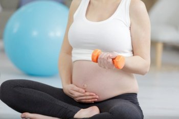 pregnant woman doing exercise with dumbbells at home