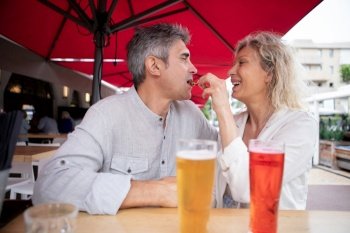 senior couple enjoying drink at outdoor bar smiling