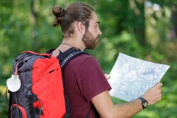 male hiker with backpack looking at map