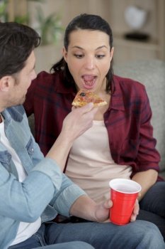 couple sharing pizza and eating together happily