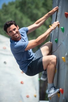man climber on artificial climbing wall in bouldering gym