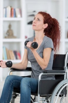 woman sitting in wheelchair working out with dumbbells