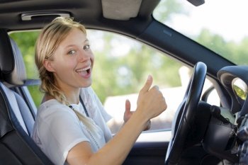 woman driving car and showing thumb up