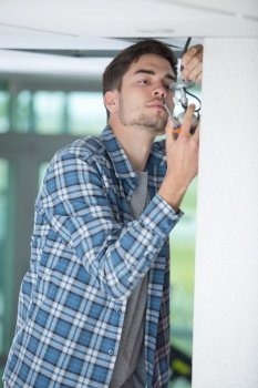 male electrician fixing light on the ceiling with screwdriver