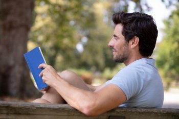 young relaxed man reading book in nature