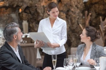friendly waitress serving meal for guests at table in restaurant