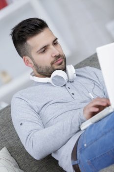 young man using headphones and laptop at home