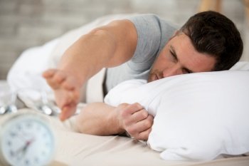 man being awakened by an alarm clock in his bedroom