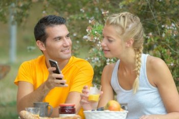man showing girlfriend his phone at breakfast table