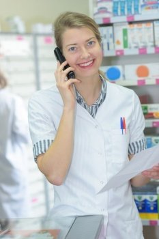 smiling pharmacist on the phone reading prescription in the pharmacy