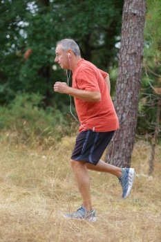 athletic mature man jogging in the forest