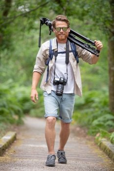 a male photographer is carrying a tripod